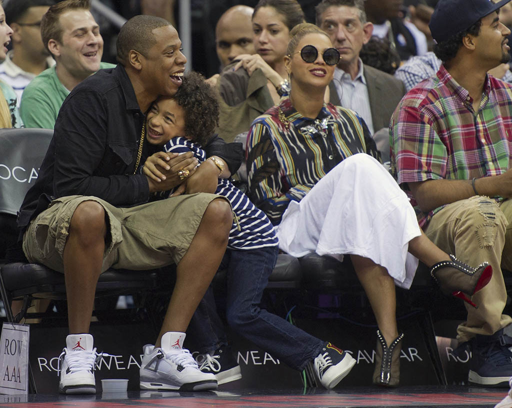 Rapper Jay-Z (L) hugs nephew Daniel Smith as his wife, singer Beyonce (2nd R) watches the New Jersey Nets play the Miami Heat in the third quarter of their NBA basketball game in Newark, New Jersey April 16, 2012. REUTERS/Ray Stubblebine (UNITED STATES - Tags: SPORT BASKETBALL ENTERTAINMENT)